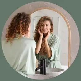 Woman looking at her skin in a mirror after an aesthetic skin treatment